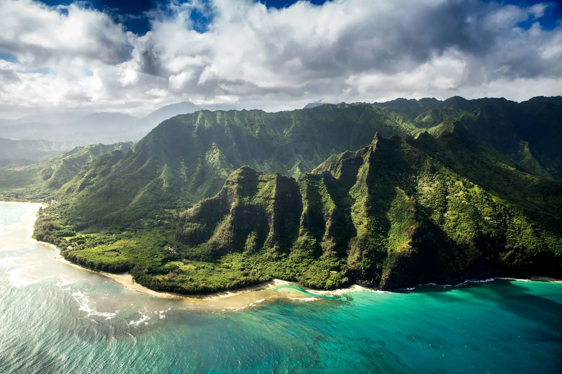 A dramatic green coastline meeting clear blue water in Hawaii